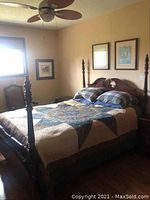 Photo showing the full bed frame from a side angle, featuring the four tall posts and headboard design.
