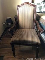 Front view of the armchair showing carved wooden frame and striped upholstery.