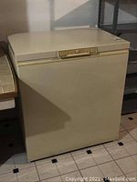 Front view of beige Kenmore chest freezer showing the full unit with lock on the lid