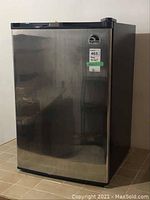 Front view of a stainless steel Igloo bar fridge model FR-465 with a sticker label on the upper right corner of the door.