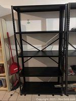 Front view of black metal shelving unit showing five shelves and frame.