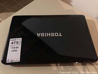 Closed Toshiba laptop with glossy black finish and Toshiba logo visible on top.