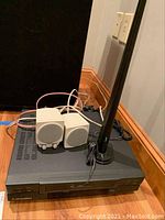 Photo showing the Mitsubishi cassette player with two white Boston speakers on top connected by wires, placed on carpeted floor.