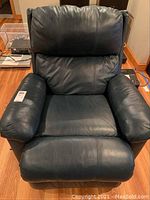 Front view of navy leather-like recliner chair showing cushioned seat, armrests, and backrest.