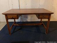 Front view of wooden desk with two drawers, showing overall structure and legs