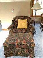 Armchair with yellow pillow and matching ottoman showing overall design and fabric pattern.