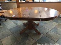 Photo of oak dining table extended with two leaves in place, showing surface and grain detail.