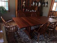 Six oak spindle-back dining chairs arranged around a table