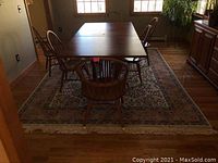 Rug under dining table revealing overall layout, color and fringe ends.