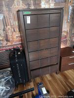 Front view of tall wooden cabinet with six drawers and label attached.