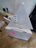 Pyramid-shaped white Luxor Light atop its box with parking tag visible