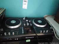 Numark IDJ3 digital DJ controller showing dual jog wheels and many control knobs and buttons, with scratches visible on the surface.