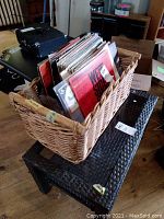 Wicker basket full of vinyl albums on black tables showing general lot contents