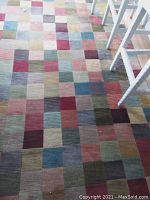 Overhead view of entire rug on hardwood floor with chairs at edge.