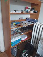 Wooden shelving displaying multiple HP ink cartridge boxes, photo paper reams, setup CD, and small items.