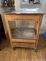 Full view of bamboo bar cart with stainless steel top, showing wine rack underneath, drawers, and caster wheels.