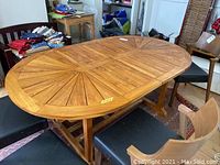 Front view of oval tabletop showing radial slat pattern and trestle legs with surrounding chairs