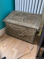Full front and angled view of the vintage metal embossed storage chest showing general shape and embossing detail.