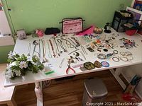 Overview of all jewelry laid out on white table along with small accessories and tools