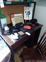 Full view of desk with wallets, pencil sharpener, puzzle box, hat, glasses cases, and painting