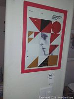 Full view of framed poster mounted on wall showing geometric shapes and profile face