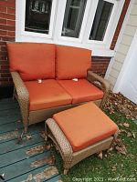 Wicker love seat and bench on deck next to brick wall, showing overall set