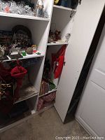 Full view of shelves with Christmas decorations, books, and table linens visible