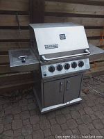 Front view of stainless steel Ducane natural gas barbecue grill with hinged lid, control panel and side shelves