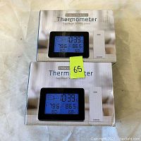Two boxed indoor/outdoor thermometers with wireless sensor modules visible on boxes.