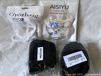 Photo showing four packs of face masks: one Gyothrig Fashion pack in white resealable bag, one AISIYU pack with floral design on front of package, and two black face mask packs in clear plastic wrapping labeled "Made in China."