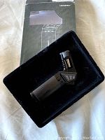 Honest butane torch lighter displayed angled on black foam tray with original box behind it.