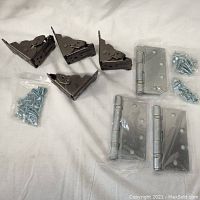 Overview photo showing all seven hinges with screws, including two standard silver hinges and five black corner hinges, all new and in plastic packaging.