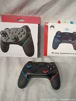 Wireless gaming controller placed in front of two original retail boxes, showing the front and back packaging with product images and branding.