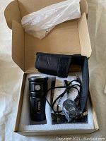 Flashlight and accessories inside open box with foam insert.