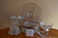 Photo showing 6 crystal and glass pieces including fruit bowl with silver trim, cake plate, pedestal candy dish, pinwheel dish, butter dish, and heart shaped trinket dish.