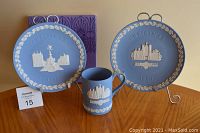Group photo showing the two Wedgwood Christmas plates from 1971 and 1980, with the 1980 mug in front, all set on a wooden surface against a plain background.