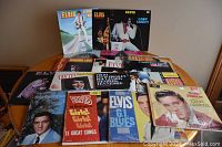 Photo showing multiple Elvis Presley vinyl LP records arranged on a surface, titles include 'Elvis,' 'I Got Lucky,' and 'Blue Hawaii'.