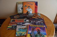 Overview of 11 vinyl LPs arranged on a round wooden table showing the album art of Jefferson Starship, Ringo, Fleetwood Mac, and others.