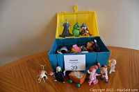 Plastic treasure chest open showing assorted colorful plastic figures inside and outside on table