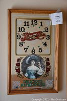 Frontal image of the Pepsi-Cola clock showing the wooden frame, mirrored clock face with Pepsi-Cola logo, vintage woman portrait, and text.