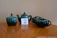 Blue Mountain Pottery teapot, creamer, oval and round sugar bowls arranged on wooden surface