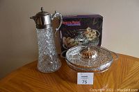 Photo showing vintage silver plate and glass pitcher with ice insert next to the hors d'oeuvre serving dish and its box on a table.