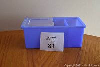 Blue plastic storage bin with three compartments: one large compartment with clear sliding lid, two smaller open compartments. Approximate size shown with ruler.