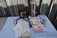 Overview of cross stitch supplies including hand towels, fabric, frames, stretch bars laid out on table.