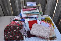 Box with assorted fabric pieces of various sizes and patterns in floral and solid color prints stacked on each other