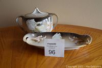 Biscuit jar with two handles and matching condiment tray placed on wooden surface, with auction number card in front