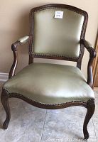 Full front view of olive green leather Chippendale style armchair showing leather upholstery and carved wooden frame.