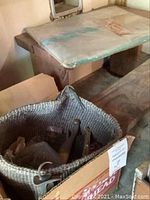 Wooden stool and a basket containing assorted metal hardware and tools together on wooden surface.