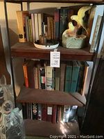 Top shelf showing vintage books, ceramic bird figurine, and ashtray.