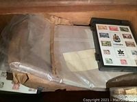Drawer interior showing various bagged stamp materials and a plastic case containing a Canada souvenir sheet